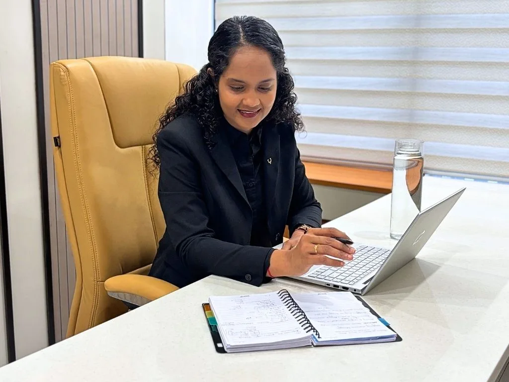 Riddhi reading a client report and writing notes at the clinic
